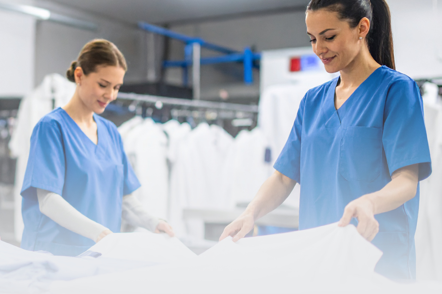 Twee dames in een wasserij die een doktersjas inspecteren
